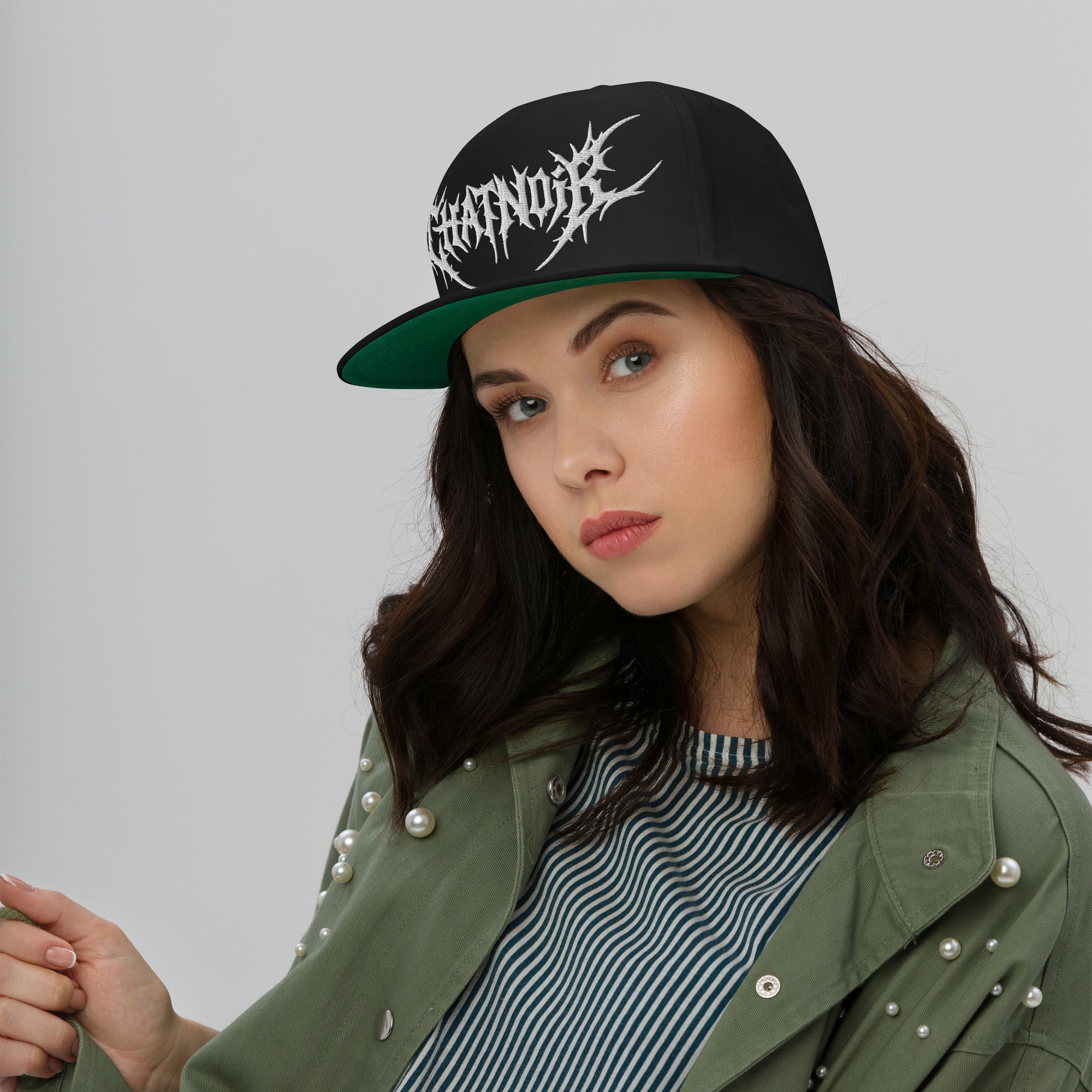 Femme portant la casquette snapback Maison Chatnoir noire avec logo brodé blanc, sous-visière verte.