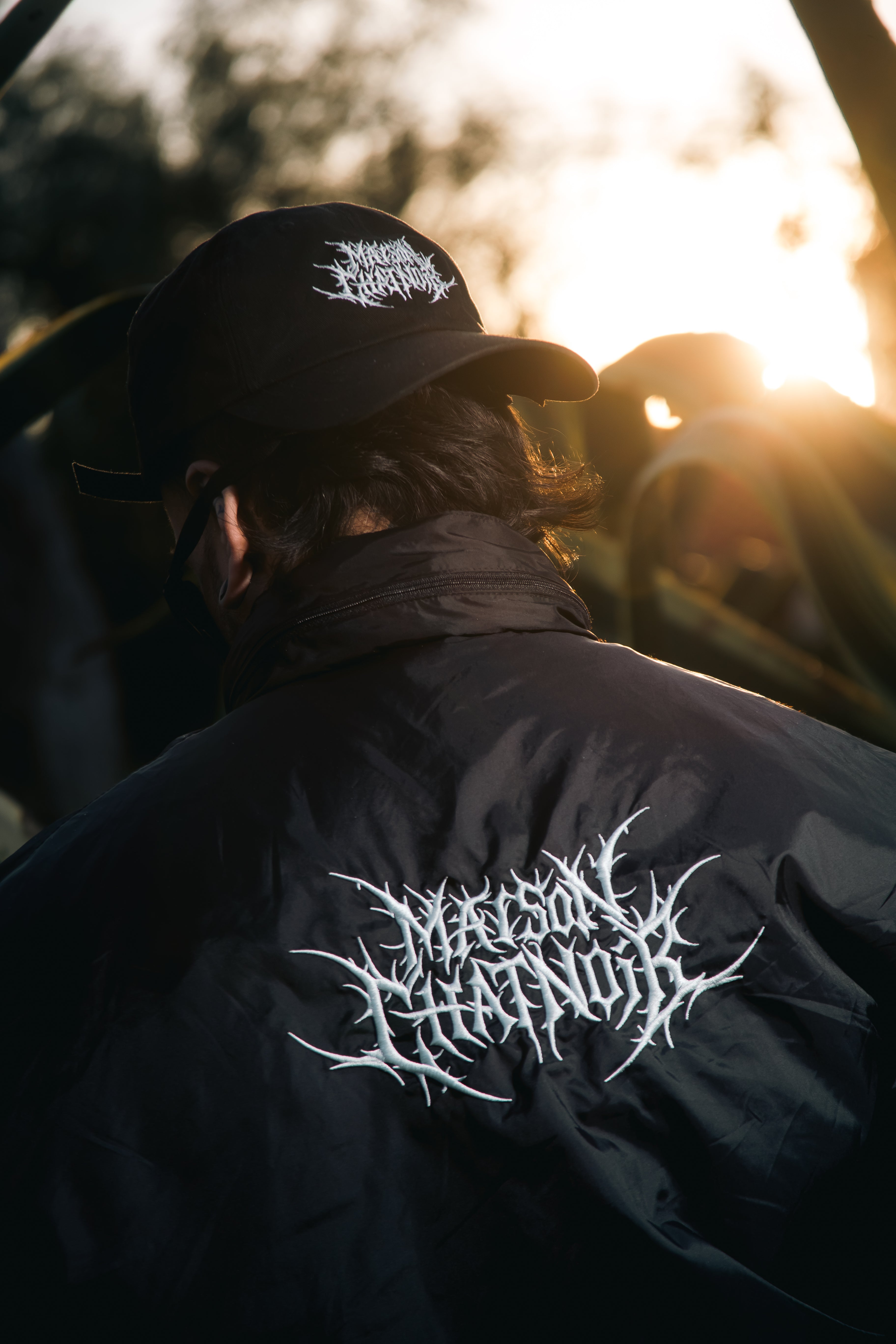 Femme portant la casquette snapback Maison Chatnoir noire avec logo brodé blanc, sous-visière verte.
